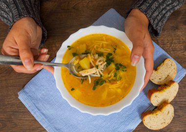 Kaşık ve kase çorba bir ahşap arka plan üzerinde holding kadın eller. Üstten Görünüm