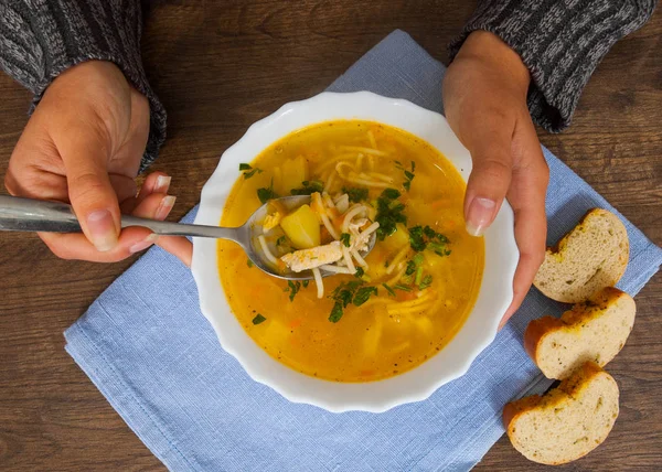 Kaşık ve kase çorba bir ahşap arka plan üzerinde holding kadın eller. Üstten Görünüm