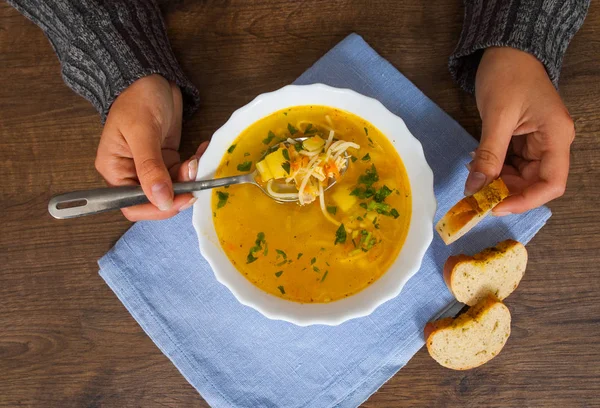 Woman hands holding spoon and bowl of soup on a wooden background. top view — Stock Image Woman hands holding spoon and bowl of soup on a wooden background. top view Royalty Free Stock Photos