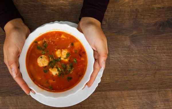Woman hands holding bowl of soup on a wooden background. top view — Stock Image Woman hands holding bowl of soup on a wooden background. top view Royalty Free Stock Images