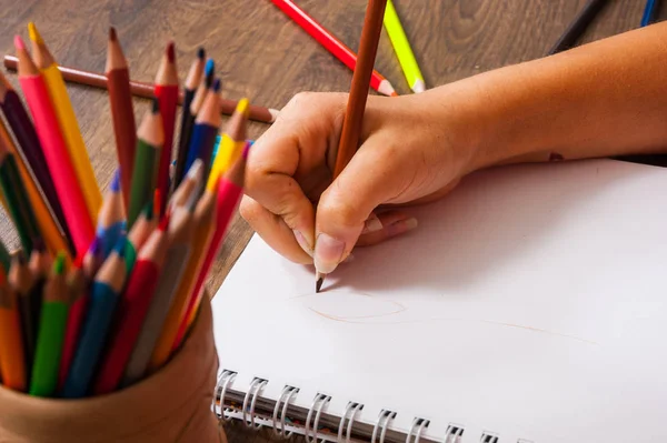 Meisje handtekening, blanco papier en kleurrijke potloden op houten tafel — Stockfoto