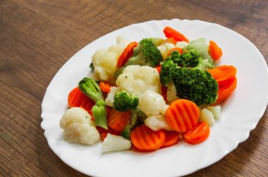 Karışık sebze. karnabahar, brokoli ve havuç plaka ahşap arka plan üzerinde.