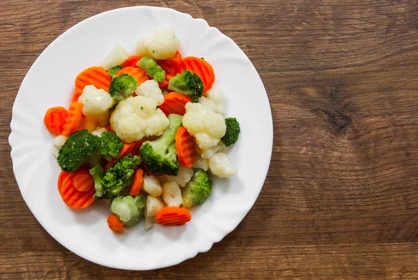 Mixed vegetables. cauliflower, broccoli and carrots in plate on a wooden background. with copy space. top view