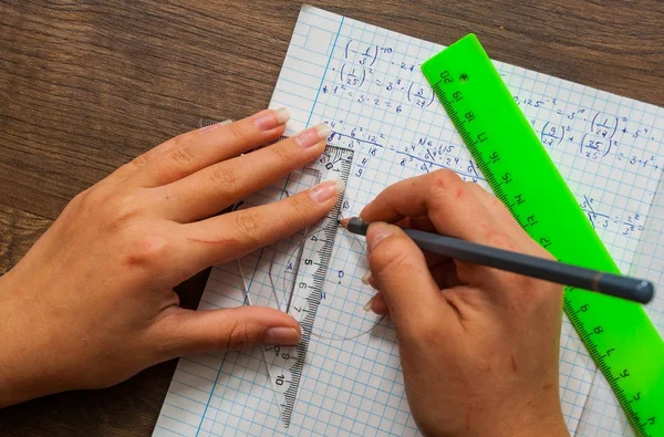 schoolgirl solves the problem of mathematics. school, education, people and learning concept - close up of student or woman hands with ruler and pencil drawing line in notebook
