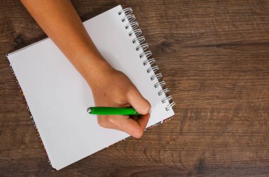 Eller kadın bir defterde bir ahşap arka plan üzerine yazma. kopya alanı ile. Üstten Görünüm