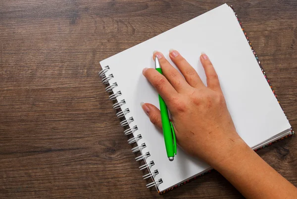 Nő kezében írásban egy notebook, egy fából készült háttér. a másolás helyet. szemközti nézet — Stock Fotó