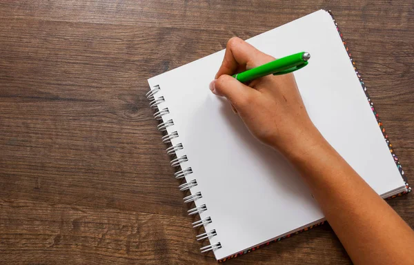 Eller kadın bir defterde bir ahşap arka plan üzerine yazma. kopya alanı ile. Üstten Görünüm