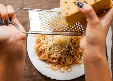 taze pişmiş spagetti peyniri beyaz tabakta domates soslu ızgara eller kadın. ahşap bir arka plan üzerinde. Üstten Görünüm