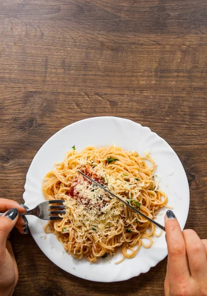 Italiensk mat. kvinnan handen håller gaffel med spaghetti bolognese i vit platta på träbord. med kopia utrymme. ovanifrån — Stockfoto