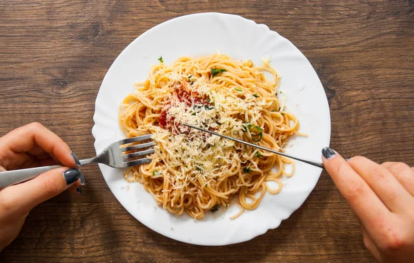 Comida italiana. tenedor de mano de mujer y cuchillo con espaguetis boloñesa en plato blanco sobre mesa de madera. vista superior —  Fotos de Stock