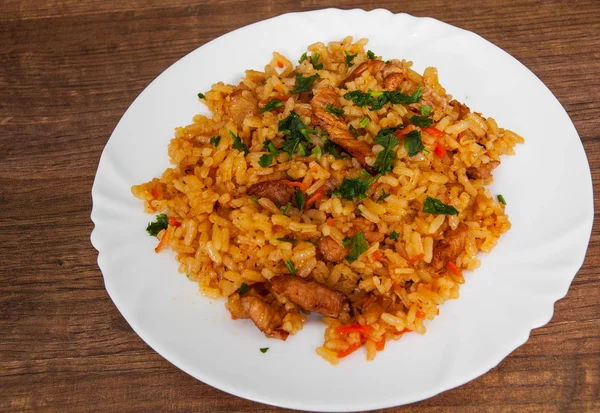 Ris med grönsaker och kött i en platta på träbord. — Stockfoto