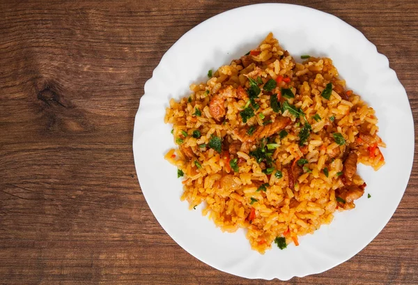 Arroz con verduras y carne en un plato sobre mesa de madera. con espacio para copias. vista superior — Foto de Stock