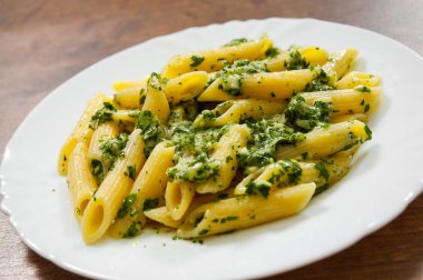 ahşap arka plan üzerinde plaka pesto soslu Penne makarna.