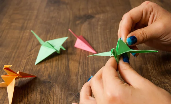 Creatività dei bambini fatta di carta, artigianato origami, artigianato per bambini. Fatto a mano. mani su tavolo di legno — Foto Stock