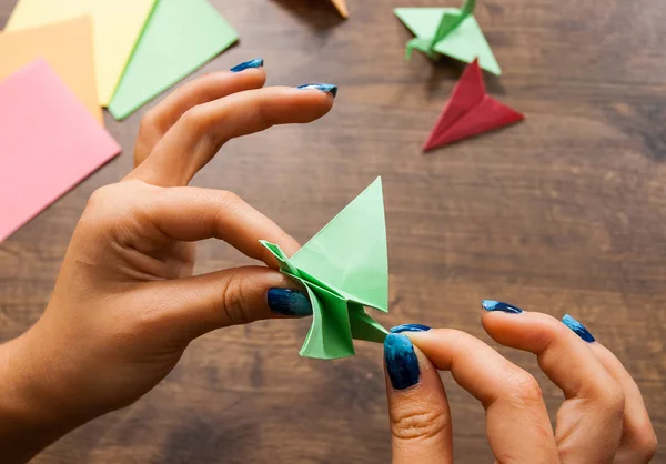 Criatividade infantil feita de papel, artesanato origami, artesanato para crianças. Feito à mão. mãos na mesa de madeira — Fotografia de Stock