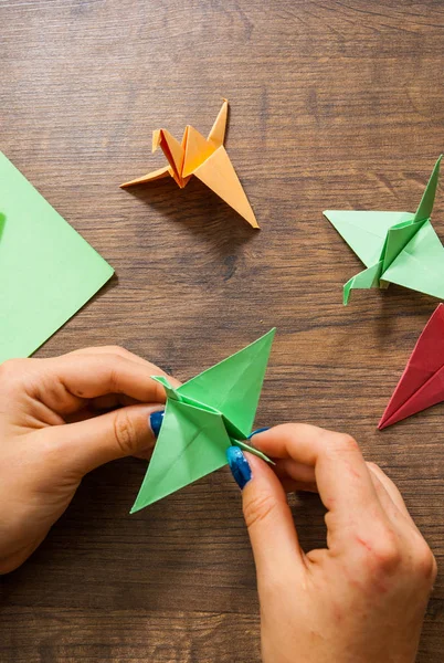 Criatividade infantil feita de papel, artesanato origami, artesanato para crianças. Feito à mão. mãos na mesa de madeira — Fotografia de Stock