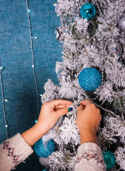 Imagen de primer plano de la mujer en jersey decorando árbol de Navidad con bolas sobre fondo azul — Foto de Stock