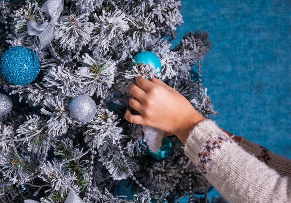 Imagen de primer plano de la mujer en jersey decorando árbol de Navidad con bolas sobre fondo azul — Foto de Stock