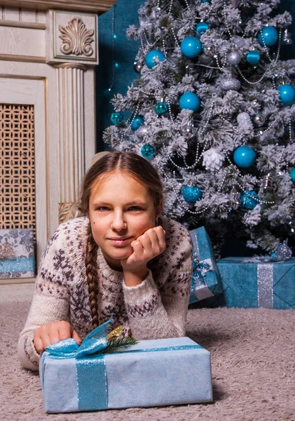 Teenager-Mädchen liegt in der Nähe eines Weihnachtsbaums mit Geschenkschachtel — Stockfoto