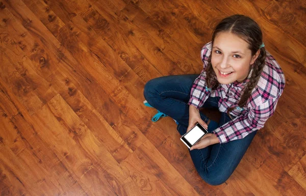 Meisje Spijkerbroek Zit Houten Vloer Het Bezit Van Een Smartphone — Stockfoto