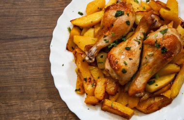 ızgara tavuk budu ve patates ahşap arka plan üzerinde beyaz tabakta. kopya alanı ile. Üstten Görünüm