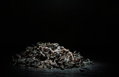 Kopya alanı ile eski koyu ahşap arka plan üzerinde yığın siyah çay yaprakları