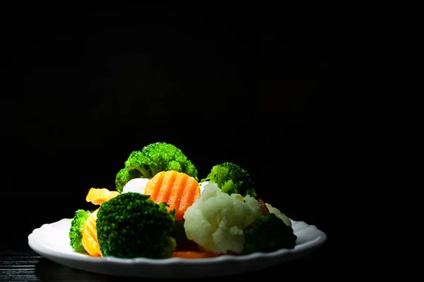 Mixed vegetables. cauliflower, broccoli and carrots in plate on the old dark wooden background with copy space