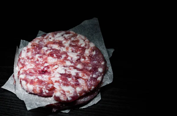 生の牛肉肉ハンバーガー ステーキ カツレツ Beefsteack 暗い背景の木に紙の上のスタック コピー スペース — ストック写真