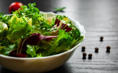 koyu ahşap arka plan üzerinde marul, radicchio ve roket kabın içinde çeşitli taze karışımı salata yaprakları