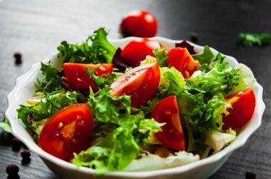 koyu ahşap arka plan üzerinde kase domates ile çeşitli taze karışımı salata yaprakları