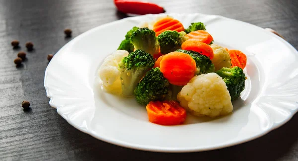 Mixed vegetables. cauliflower, broccoli and carrots in plate on a dark wooden background