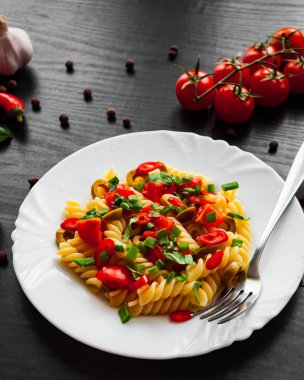 Düdük makarna salatası plaka koyu ahşap zemin üzerine zeytin ve domates ile