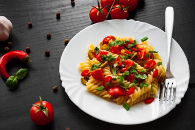 Düdük makarna salatası plaka koyu ahşap zemin üzerine zeytin ve domates ile