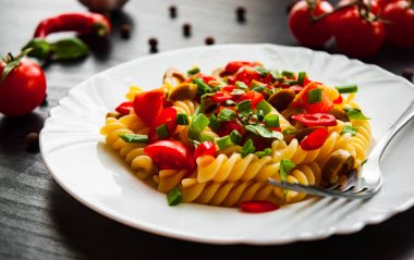 Düdük makarna salatası plaka koyu ahşap zemin üzerine zeytin ve domates ile