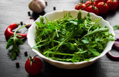 Yeşil rucola koyu ahşap arka plan üzerinde beyaz kase taze salata