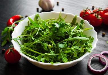 Yeşil rucola koyu ahşap arka plan üzerinde beyaz kase taze salata