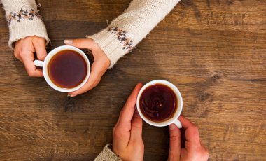 Erkeklerin ve kadınların elinde bir fincan siyah çay. Tahta bir arka planda. Fotokopi alanı. en üstteki görünüm