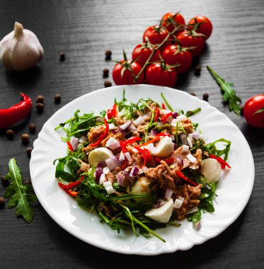 Yeşil rucola, peynir, ton balığı, soğan, taze salata koyu ahşap arka plan üzerinde beyaz kase biber