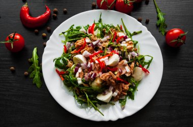 Yeşil rucola, peynir, ton balığı, soğan, taze salata koyu ahşap arka plan üzerinde beyaz kase biber