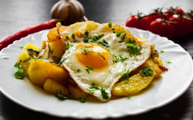 kızarmış yumurta koyu ahşap zemin üzerine bir tabak patates ile