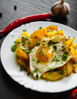 kızarmış yumurta koyu ahşap zemin üzerine bir tabak patates ile