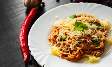 Makarna spagetti domates sosu ve koyu ahşap zemin üzerine rendelenmiş peynir ile