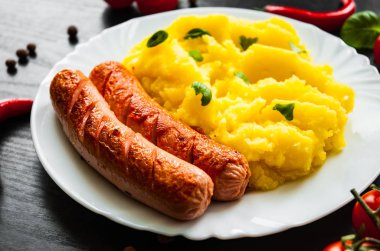 kızarmış et sosis koyu ahşap zemin üzerine bir tabak patates püresi ile