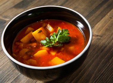 Ahşap masa üzerinde seramik kase sebze ve fasulye çorbası