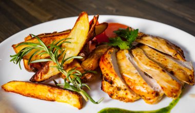 Ahşap masa üzerinde bir tabak patates ile ızgara tavuk göğsü