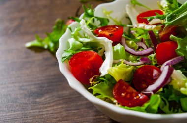 ahşap arka plan üzerinde kase domates ile çeşitli taze karışımı salata yaprakları