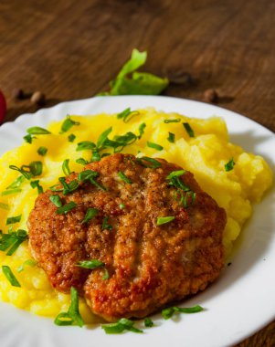 ahşap arka plan üzerinde beyaz tabak patates püresi ile kavrulmuş burger