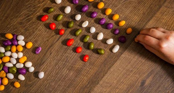Kadın Eli Bir Ahşap Arka Plan Üzerinde Renkli Şekerler Bile — Stok fotoğraf