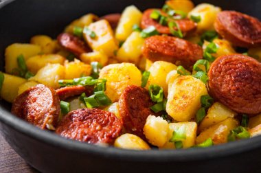 Kavrulmuş patates ve sosis tavada ahşap masa