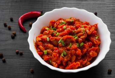 Koyu ahşap arka plan üzerinde kapta domates soslu sebze ve fasulye güveç